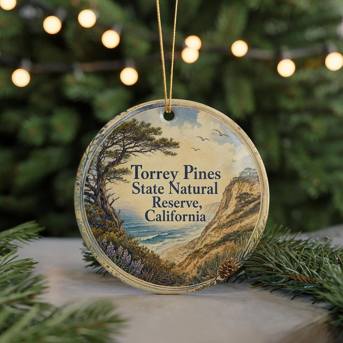 A round ornament with a scenic landscape of Torrey Pines State Natural Reserve, California, featuring a pine tree, mountains, and a body of water.