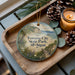 A wooden tray with a decorative ornament featuring a scenic view of Traverse City State Park, Michigan, along with pine cones and a lit candle.