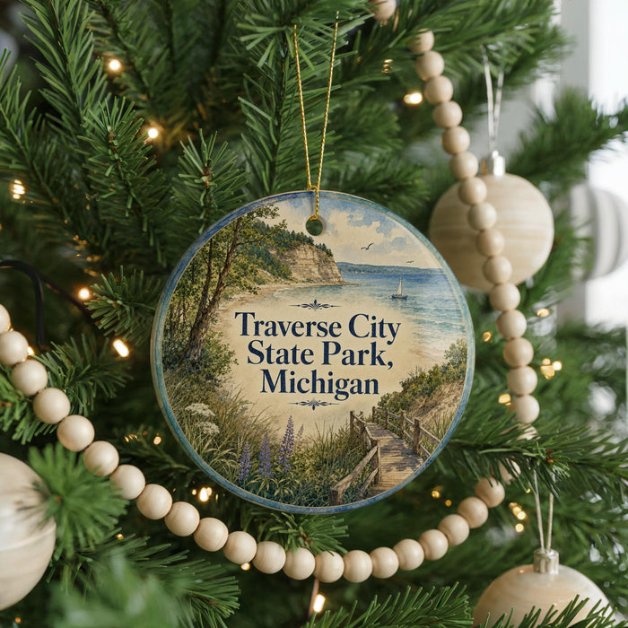 A round ornament hanging on a Christmas tree, featuring a scenic image of Traverse City State Park, Michigan.