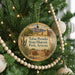 A round ornament hanging on a Christmas tree, featuring a desert landscape with mountains in the background.