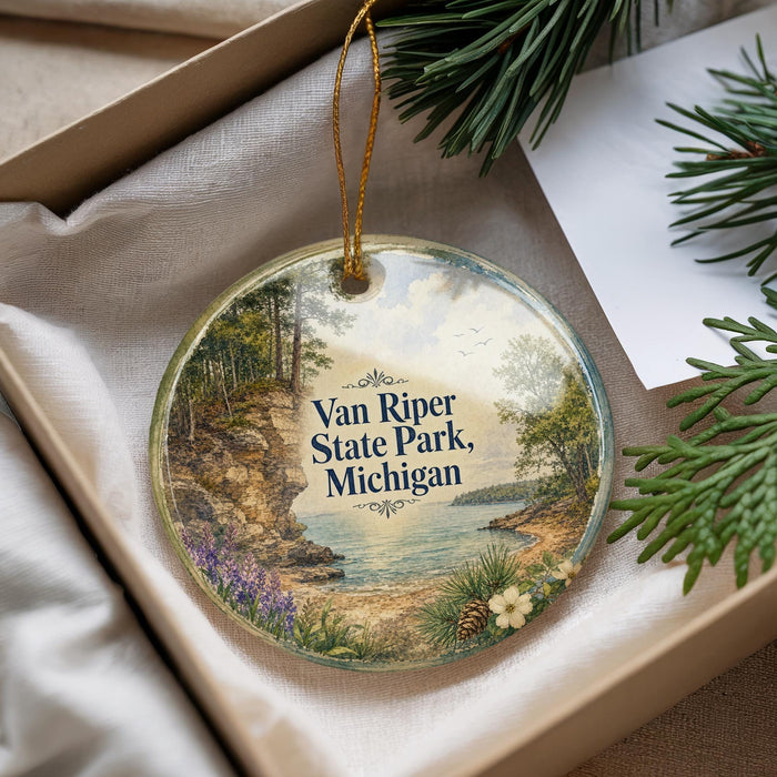A decorative ornament with a scenic landscape of Van Riper State Park, Michigan, featuring a lake, pine trees, and a rocky cliff.
