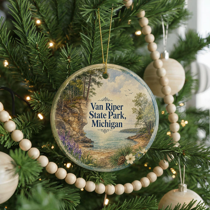 A round ornament hanging on a Christmas tree, featuring a scenic landscape with a lake and mountains.