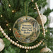 A round ornament hanging on a Christmas tree, featuring a scenic landscape with mountains, a waterfall, and a clock tower.