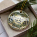 A decorative ornament with a scenic image of Victoria Falls and State Park in Georgia, displayed in a box with pine branches.