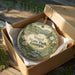 A decorative ornament in a box, featuring a scenic landscape with mountains, trees, and a bird, along with the text "Vogel State Park, Georgia".