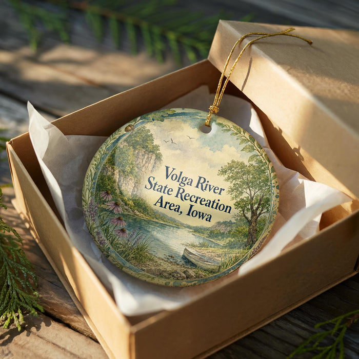 A decorative ornament in a wooden box, featuring a scenic landscape with a river, trees, and a boat.