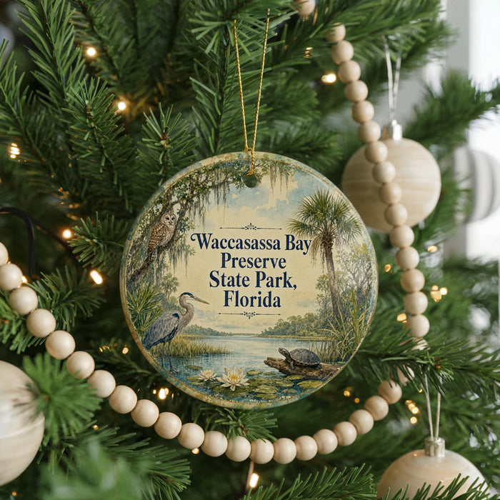A circular ornament hanging on a Christmas tree, featuring a bird, a turtle, and palm trees, with the text "Wacassassa Bay Preserve State Park, Florida" displayed on it.