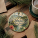 A circular ornament with a tropical landscape design, featuring a river, palm trees, and a bridge, is displayed on a wooden surface alongside a cup of coffee and some papers.