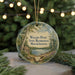 A round ornament with a scenic landscape of Walden Pond, featuring a cabin and trees, is displayed in front of a blurred background with Christmas lights.