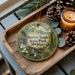 A wooden tray with a decorative ornament featuring a scenic image of Warren Woods State Park, Michigan, and pine cones.
