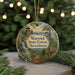 A round ornament with a scenic forest landscape and a lighthouse in the background, hanging on a string.