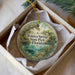 A circular ornament with a scenic image of Wekiva Springs State Park, Florida, displayed in a box with a white tissue paper lining.