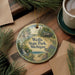 A round ornament with a scenic illustration of Wells State Park, Michigan, featuring a bird, a cabin, and a waterfall.