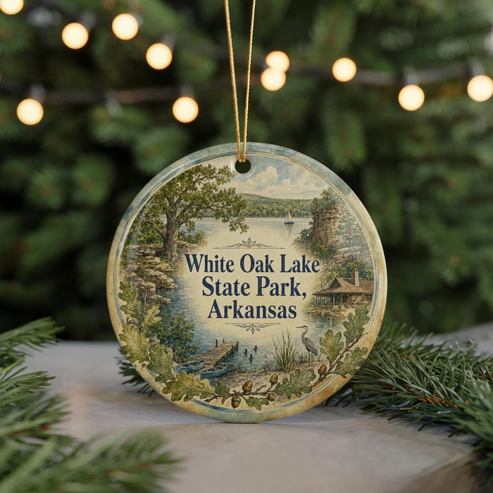A decorative ornament featuring a scenic landscape of White Oak Lake State Park in Arkansas, with a lake, trees, and a cabin in the background.