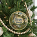 A circular ornament hanging on a Christmas tree, featuring a scenic landscape with a waterfall and pine trees.