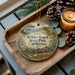 A wooden tray with a decorative ornament featuring a scenic landscape of Wilder Ranch State Park, California, and pine cones.