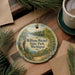 A decorative ornament featuring a scenic image of William Mitchell State Park in Michigan, with pine branches and a cup of coffee nearby.