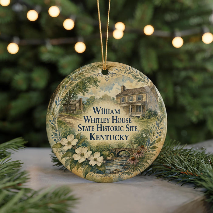 A round ornament with a painting of a historic house and a wreath, surrounded by greenery and white flowers, with the text "William Whitley House State Historic Site, Kentucky" displayed on it.