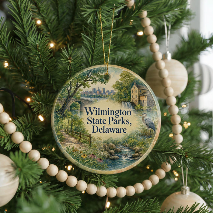 A round ornament hanging on a Christmas tree, featuring a scenic landscape with a waterfall and a bridge.