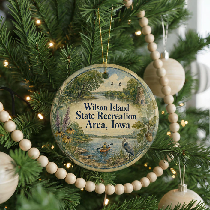 A round ornament on a Christmas tree, featuring a scenic landscape with a river, trees, and a bird, along with the text "Wilson Island State Recreation Area, Iowa".