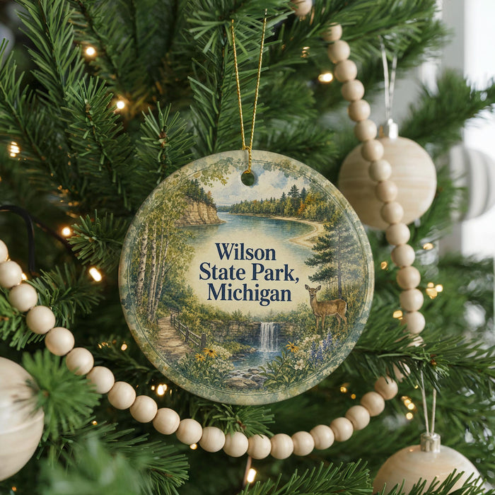 A round ornament on a Christmas tree, featuring a scenic landscape with a lake, forest, and waterfall.