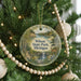 A round ornament on a Christmas tree, featuring a scenic landscape with a lake, forest, and waterfall.