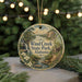 A round ornament with a scenic landscape of Wind Creek State Park, Alabama, featuring a waterfall, forest, and a cabin.