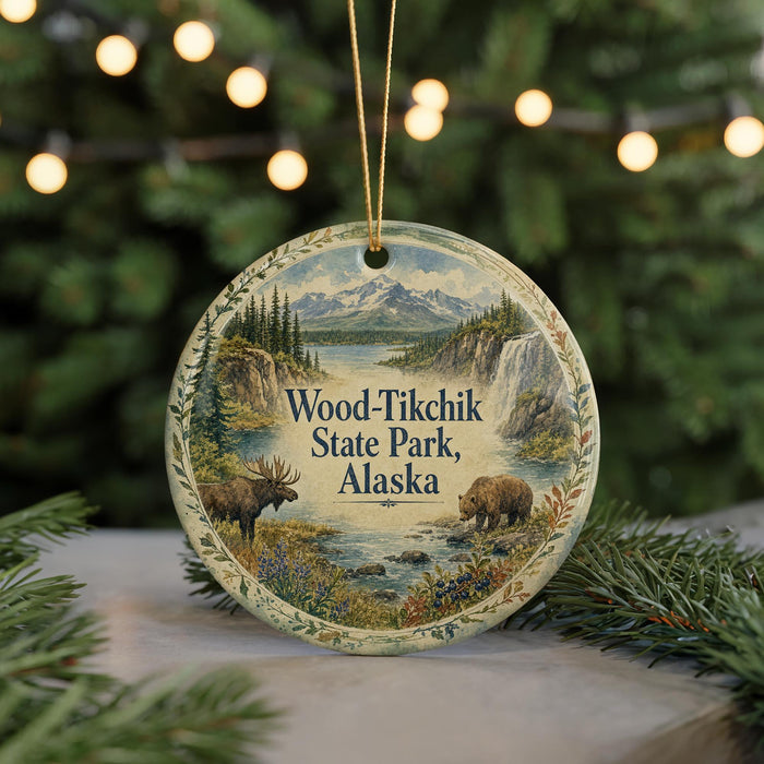 A circular ornament featuring a scenic landscape with moose and bears, surrounded by pine trees and mountains, with the text "Wood-Tikchik State Park, Alaska" displayed prominently.