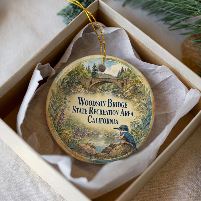 A decorative ornament in a box, featuring a scenic image of the Woodson Bridge and the surrounding landscape.