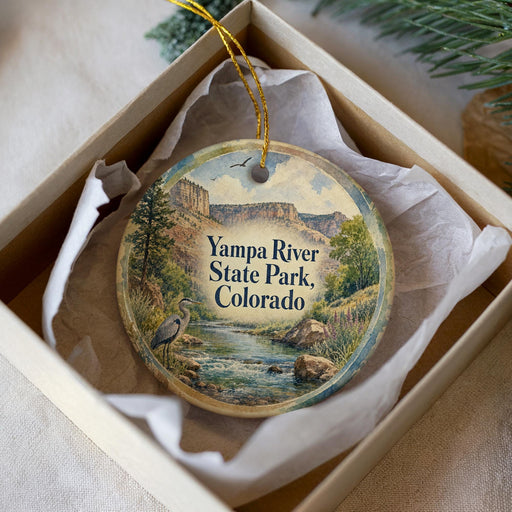 A decorative ornament in a box, featuring a scenic image of the Yampa River State Park in Colorado.
