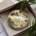 A decorative ornament in a box, featuring a scenic image of the historic Bluff Fort in Florida.