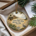 A decorative ornament with a painting of a historical state park, featuring palm trees and a bird, is displayed in a box with pine branches.