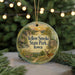 A decorative ornament featuring a scenic landscape with a deer, trees, and a sunset, hanging from a string.
