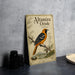 A vintage-style metal calendar featuring an illustration of an orange and black oriole bird perched on a branch, with text describing the bird species.