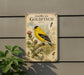 a vintage-style metal sign with an illustration of a goldfinch bird, surrounded by plants and flowers, mounted on a wall.