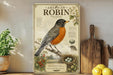 a vintage-style illustration of a robin, with detailed illustrations of the bird, its nest, and surrounding flora.