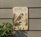 a vintage-style metal sign with an illustration of a bird perched on a pine branch, mounted on a wall.