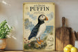 A vintage-style poster of an Atlantic puffin, a type of seabird, is displayed on a wall next to a wooden cutting board and some kitchen utensils.