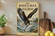 A framed poster of a bald eagle with salmon on a shelf, surrounded by kitchen utensils and a potted plant.