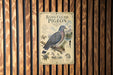 A metal sign with an illustration of a band-tailed pigeon mounted on a wooden wall.