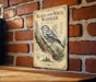 a vintage-style metal sign with a black and white illustration of a bird perched on a branch, mounted on a brick wall.