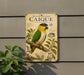 a sign with a colorful illustration of a parrot, specifically a Black-headed Caique, perched on a branch.