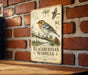 A vintage-style metal sign with illustrations of a Blackburnian Warbler perched on a branch, mounted on a brick wall.