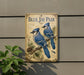 A vintage-style metal sign featuring illustrations of two blue jays perched on branches, with pine cones and pine needles in the background.