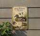 a vintage-style metal sign with illustrations of blue-winged teal ducks, mounted on a wall next to a plant.