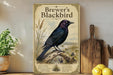 A vintage-style poster of a blackbird is displayed on a shelf, accompanied by a wooden cutting board, a potted plant, and some lemons.