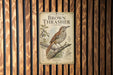 a sign with a brown thrush bird illustration, mounted on a wooden wall.