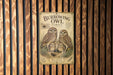 a poster of Burrowing Owls, a family of owls, displayed on a wooden wall.