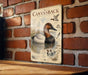 a vintage-style metal sign with a detailed illustration of a canvasback duck, mounted on a brick wall.