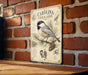a vintage-style metal sign with illustrations and text about the Carolina Chickadee, a small bird species.